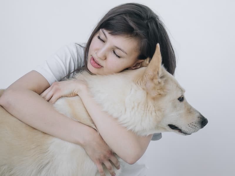 girl showing love to her dog by hugging it